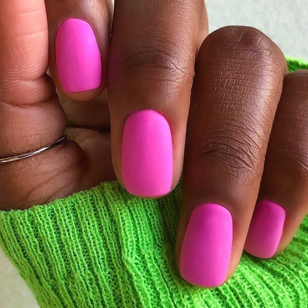 Close-up of hand with bright pink manicured nails and a green sweater sleeve