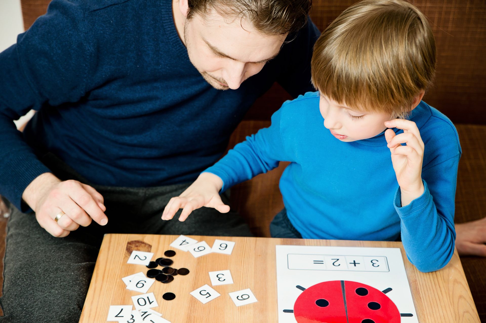 Ein Mann und ein Junge spielen an einem Tisch ein Spiel.