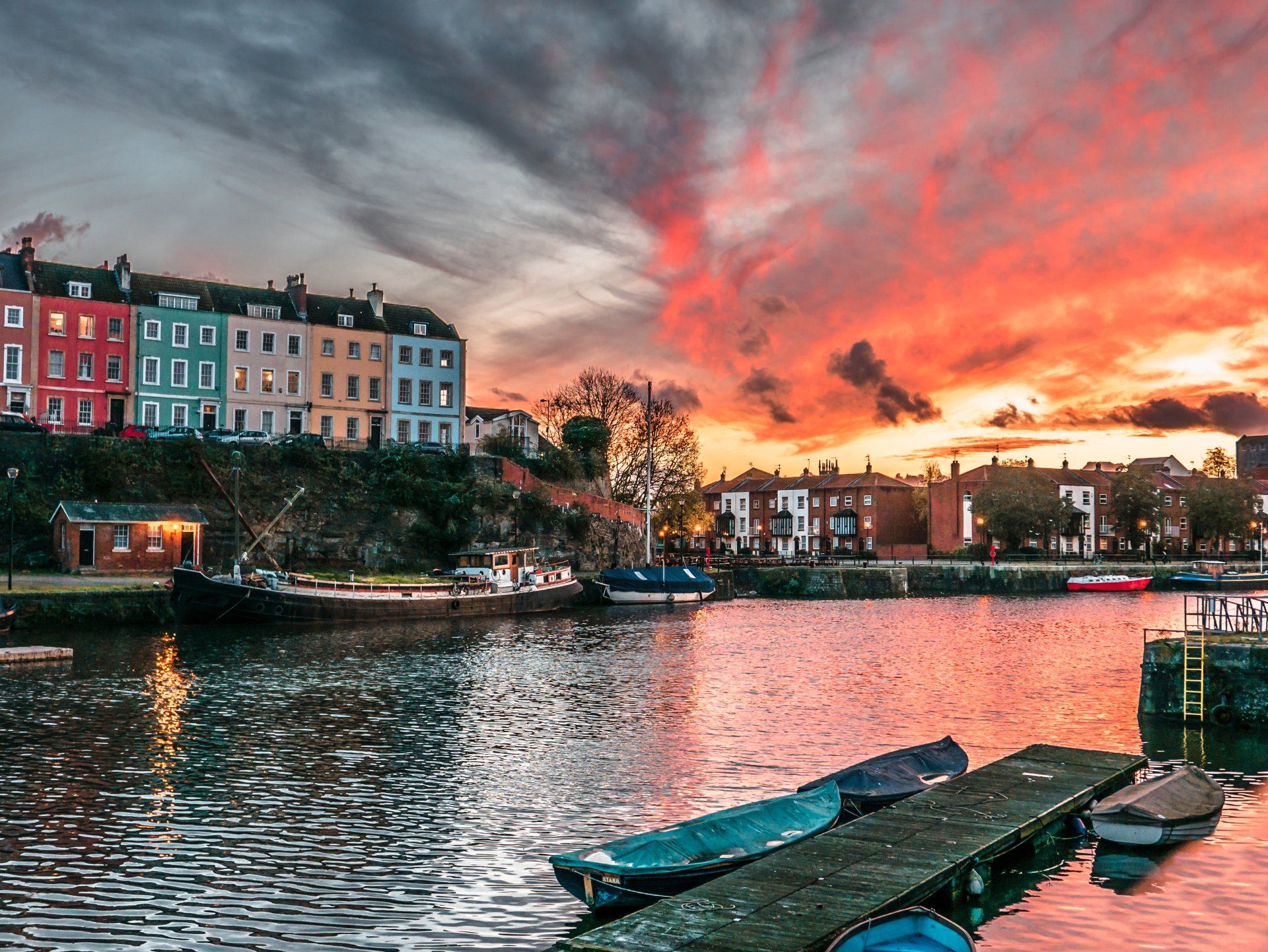 A sunset over a body of water with boats docked on a dock.