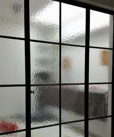 Frosted glass office window with blurred silhouettes and black grid framing