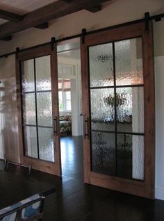 Wooden sliding glass doors with frosted panels opening into a bright room with hardwood floors