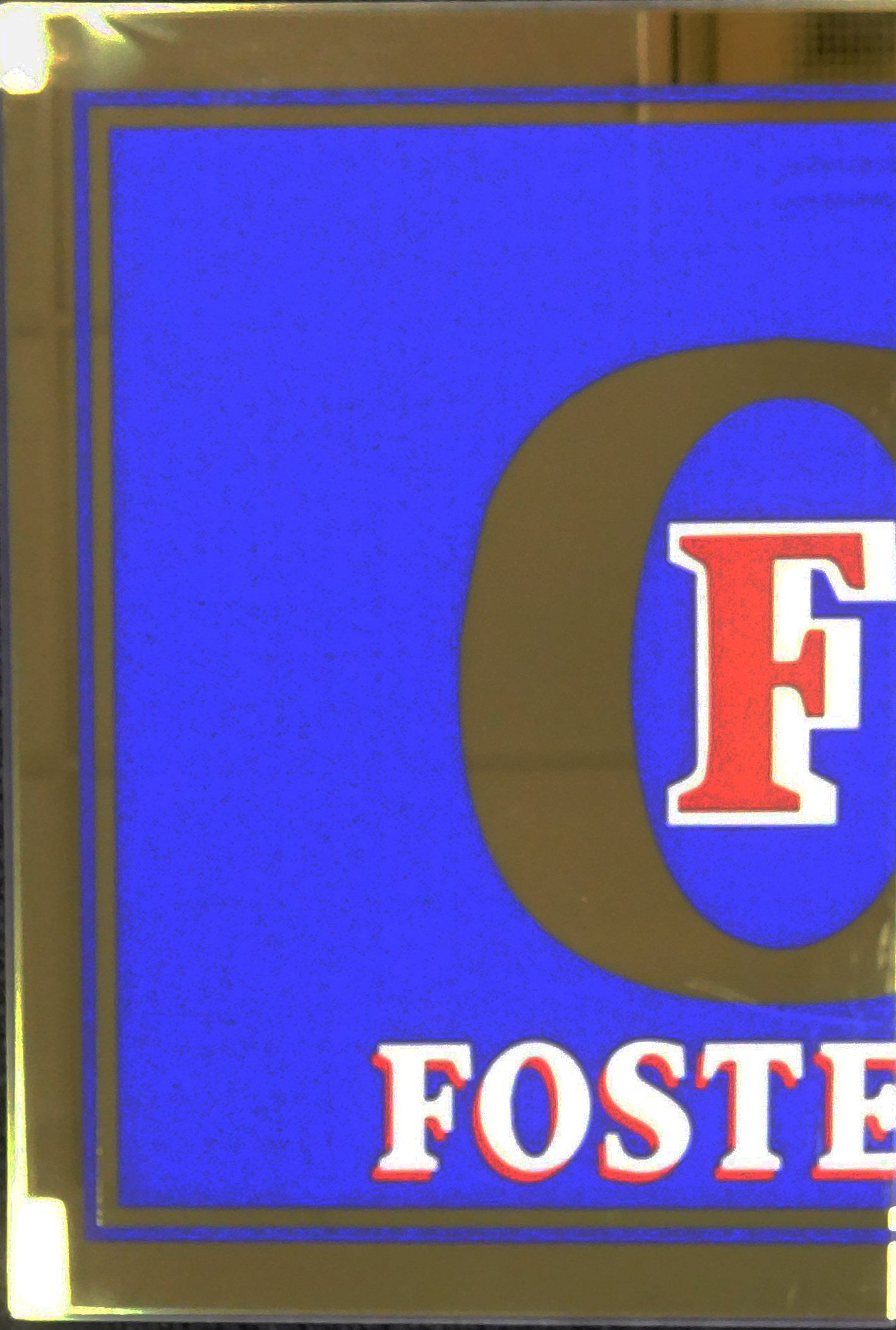 Close-up of a blue Foster’s sign with a red-and-white “F” logo and gold border.