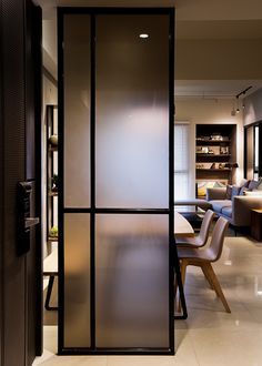 Modern interior with a frosted glass and black-framed partition beside a dining area.