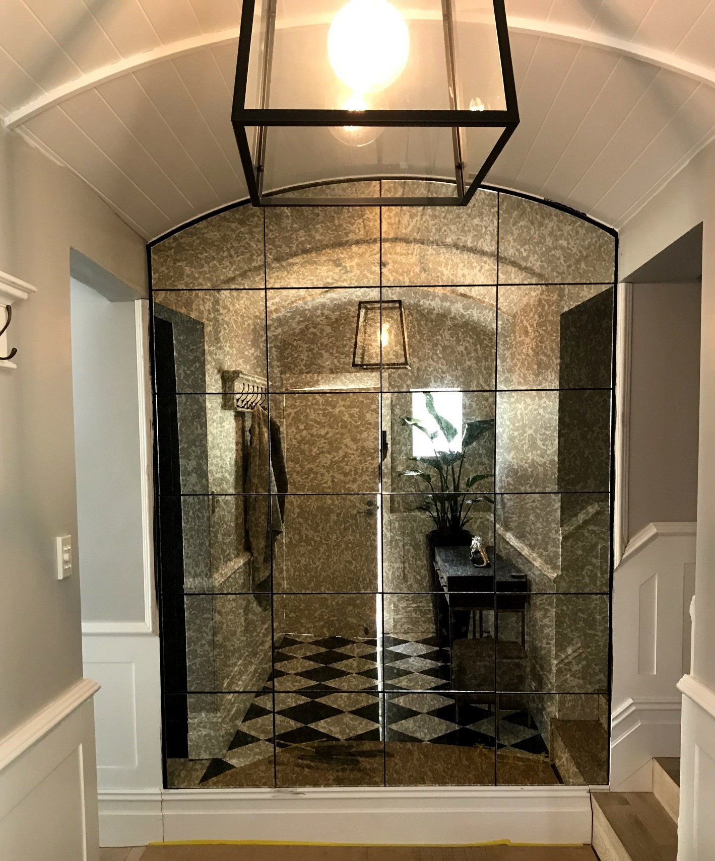 Glass-enclosed shower with black-and-white tile in a bright bathroom hall