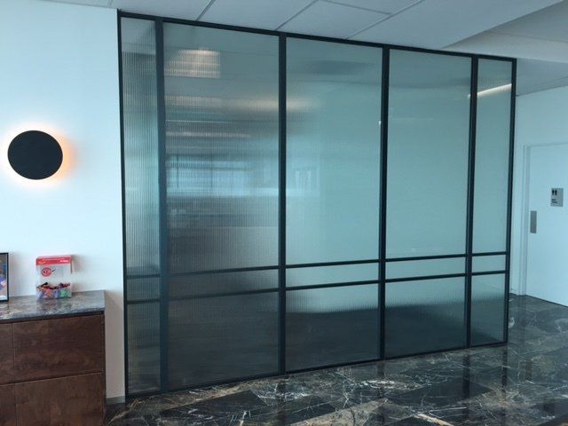 Modern office lobby with black-framed glass partition and marble floor