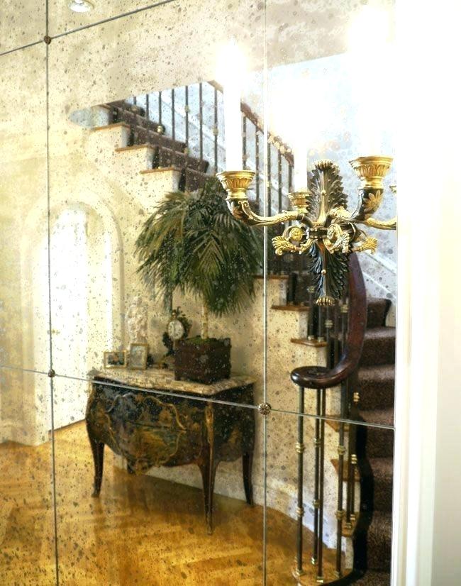 Antique console table with mirror, floral arrangement, and gold candelabra in a bright entryway