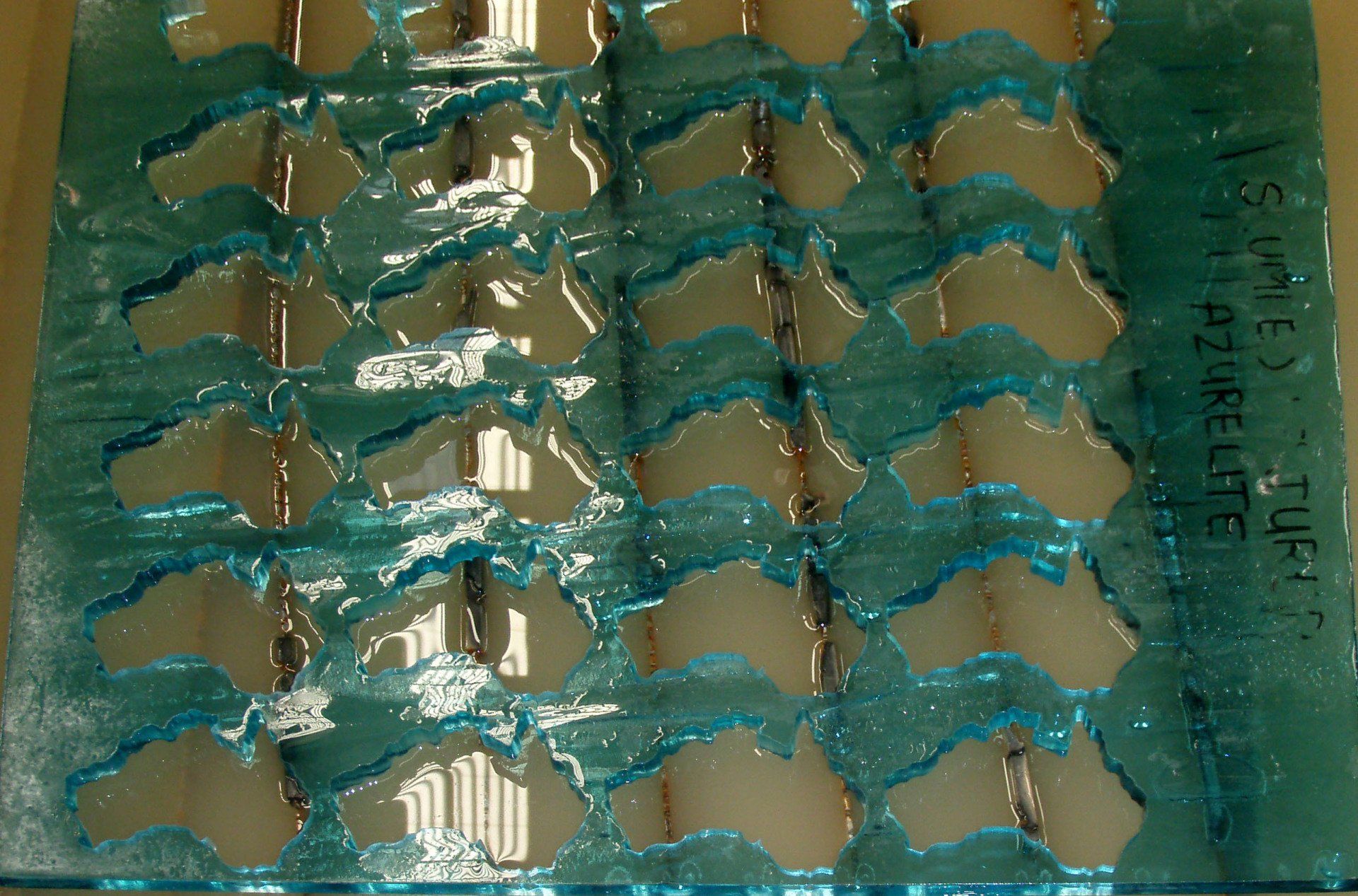 Close-up of blue-green blister packs with shiny silver capsules in rows