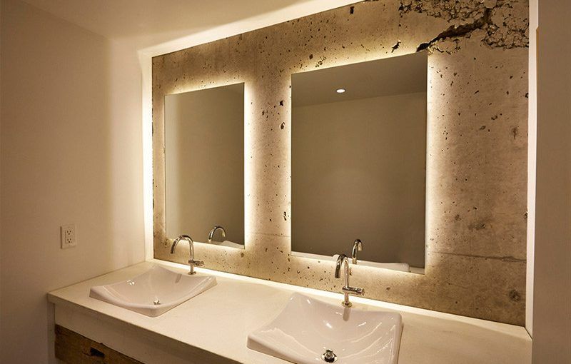 Modern bathroom with double sinks and backlit mirrors above a marble countertop