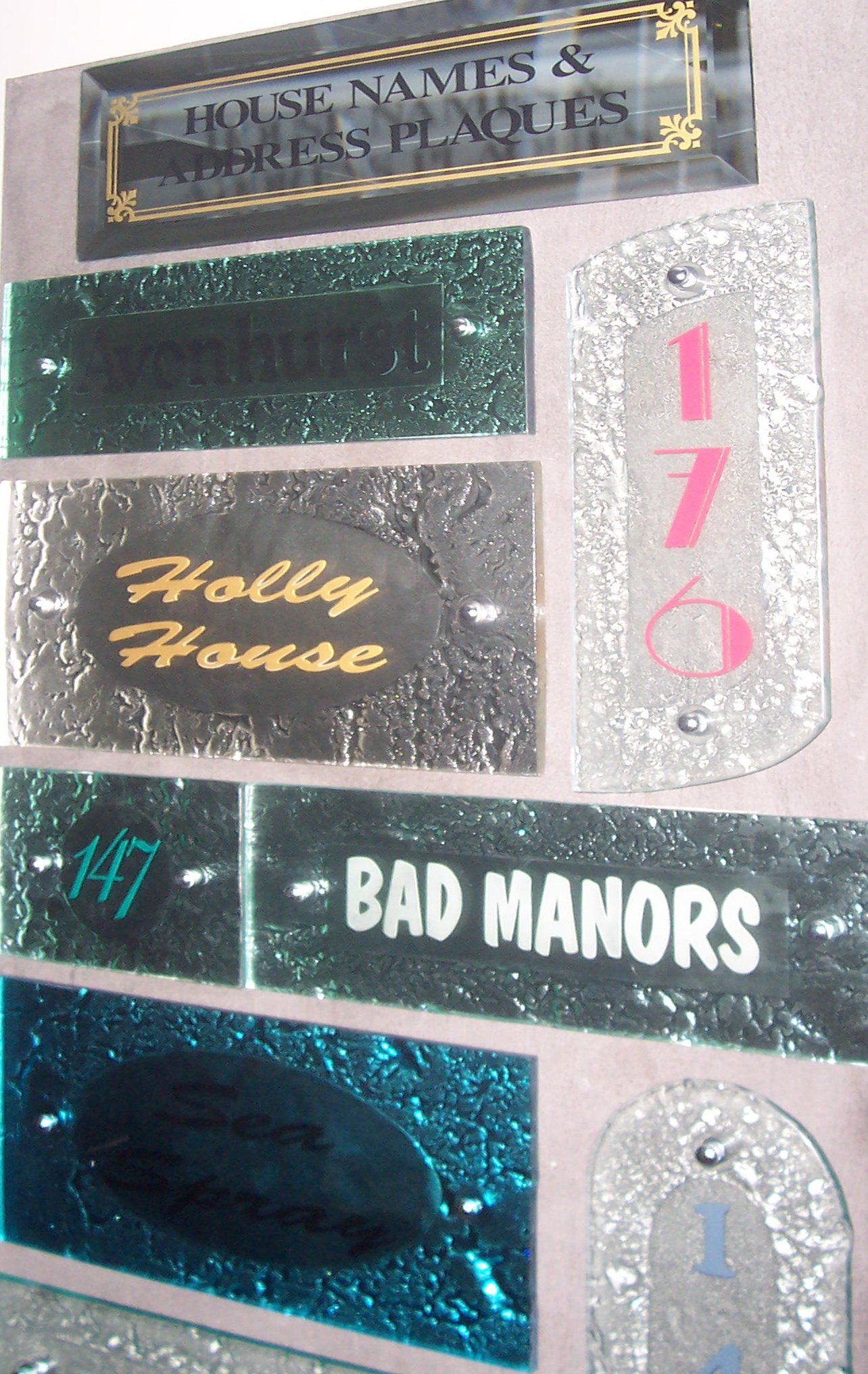 Assorted glittery venue plaques and signs, including “BAD MANORS,” “Holly House,” and the number 176.