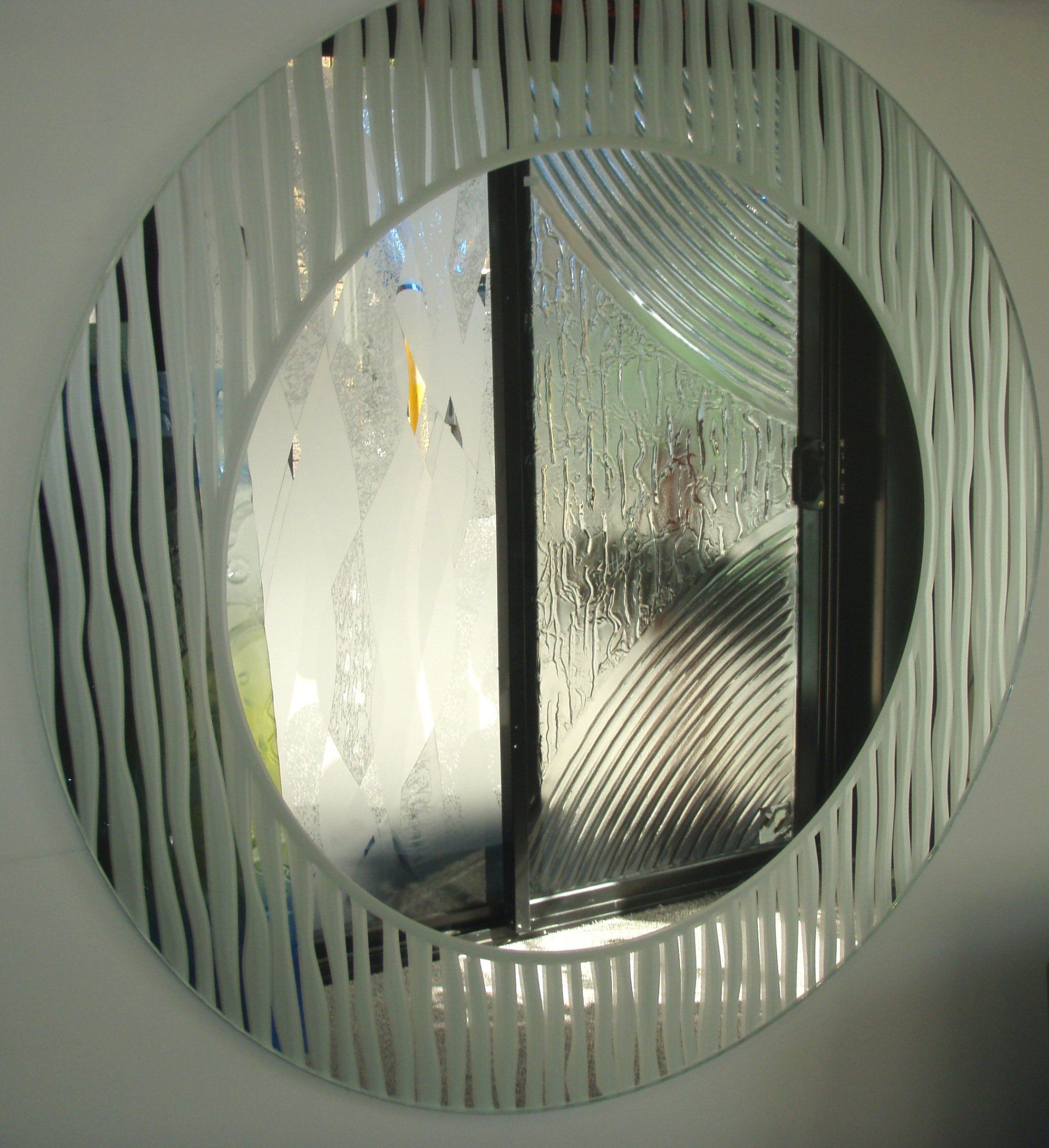 Round frosted-glass wall mirror reflecting a window and vertical blinds