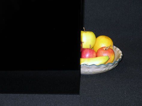 Fruit bowl partly hidden behind a black panel on a dark background