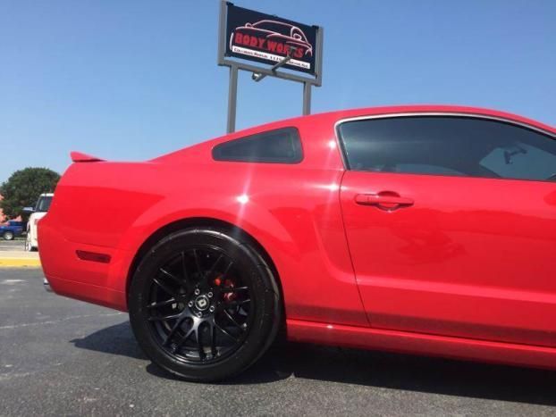 A red car is parked in front of a sign that says liberty auto