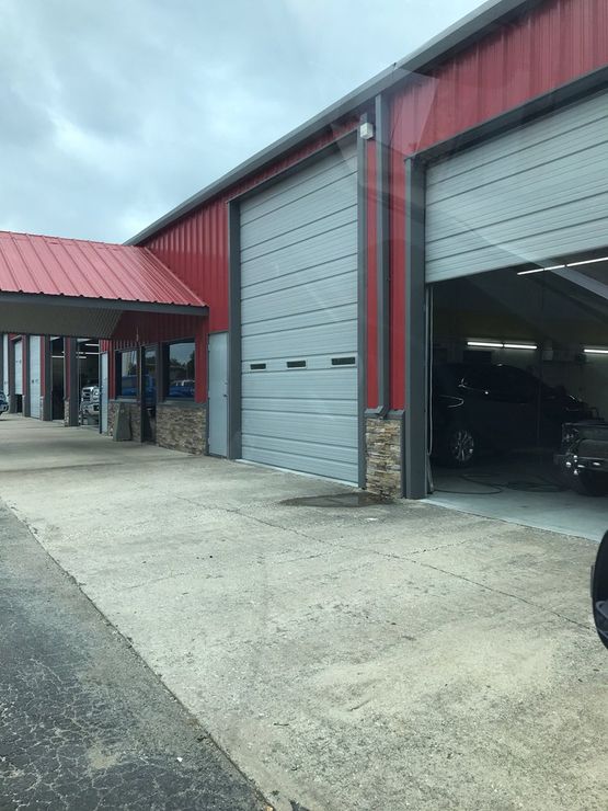A car is parked in front of a garage with a red roof.