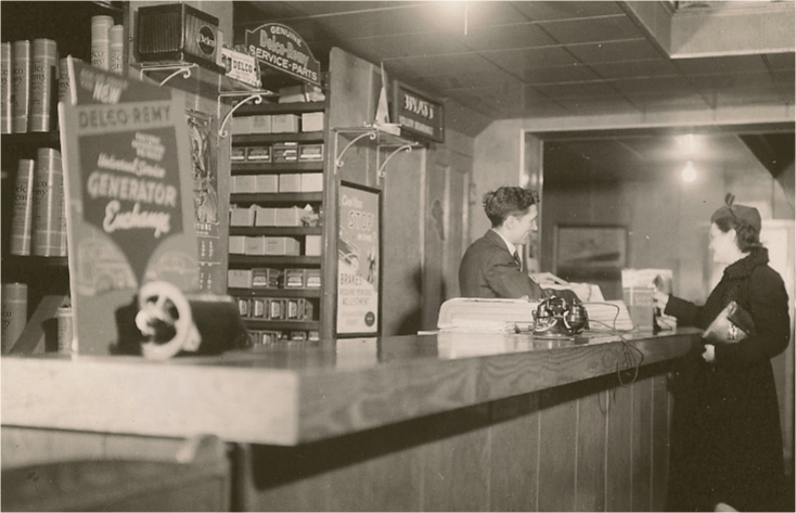 A customer at a counter in a vintage store, interacting with a clerk. Shelves, products, and signs are visible.