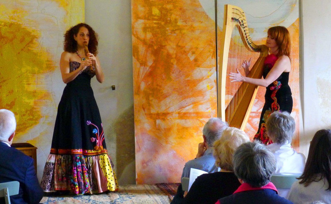 Two women playing instruments in front of a crowd of people.