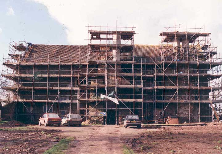 Acton Court with scaffolding around it and cars parked in front of it