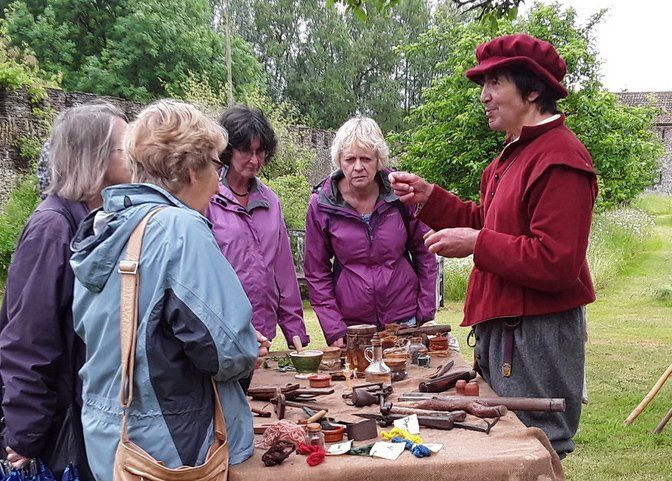 A group of people are standing around a table talking to a man in a red hat.