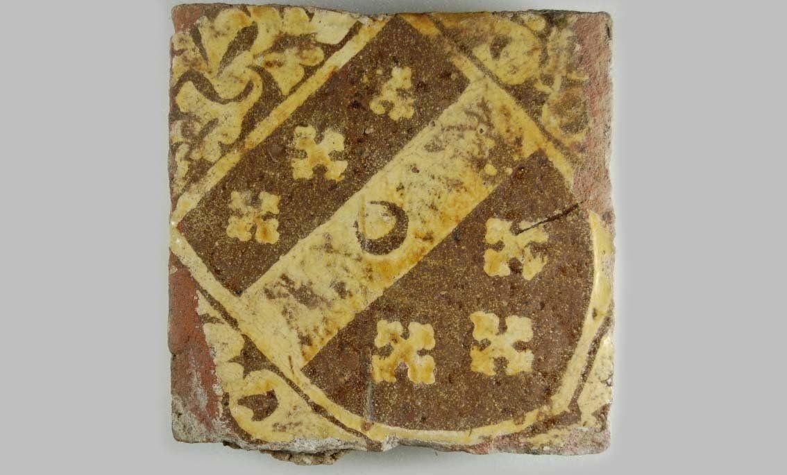 A brown and yellow Tudor tile with a coat of arms on it.