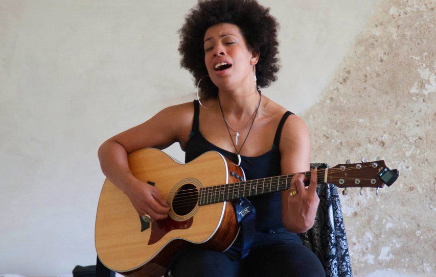 A woman is singing while playing an acoustic guitar