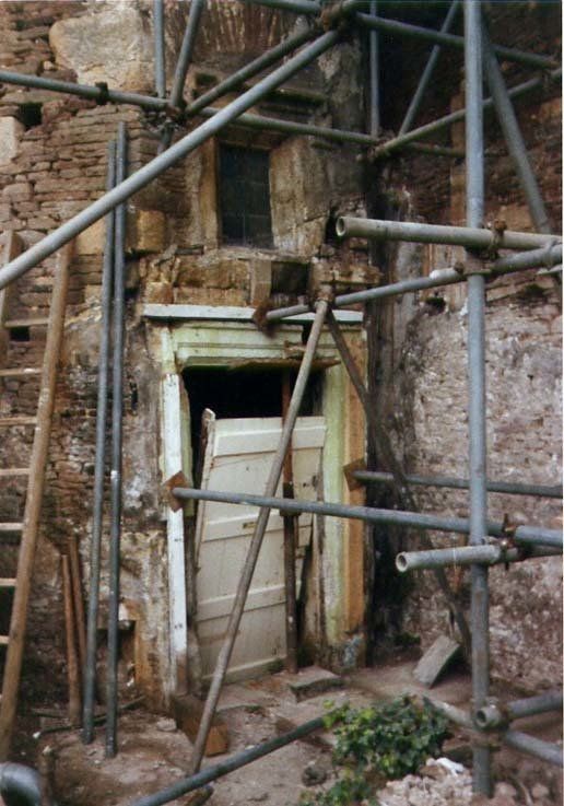 A brick building with a door and scaffolding around it at Acton Court