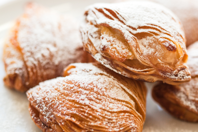 Un primo piano di un mucchio di pasticcini con zucchero a velo su un piatto.