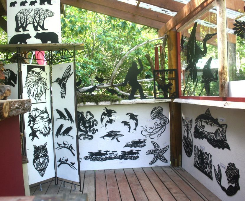 Open-air art display of black animal silhouettes on white panels and red railings in a wooden pavilion