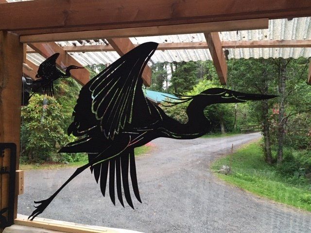Black bird silhouette decal on a glass door, with a driveway and green trees visible outside.