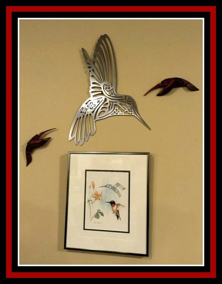 Framed bird artwork on a beige wall with three decorative flying bird sculptures around it