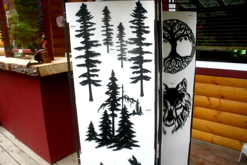 Decorative white panels with black pine tree silhouettes leaning outside a wooden building