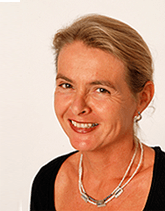 A woman wearing a necklace and earrings smiles for the camera