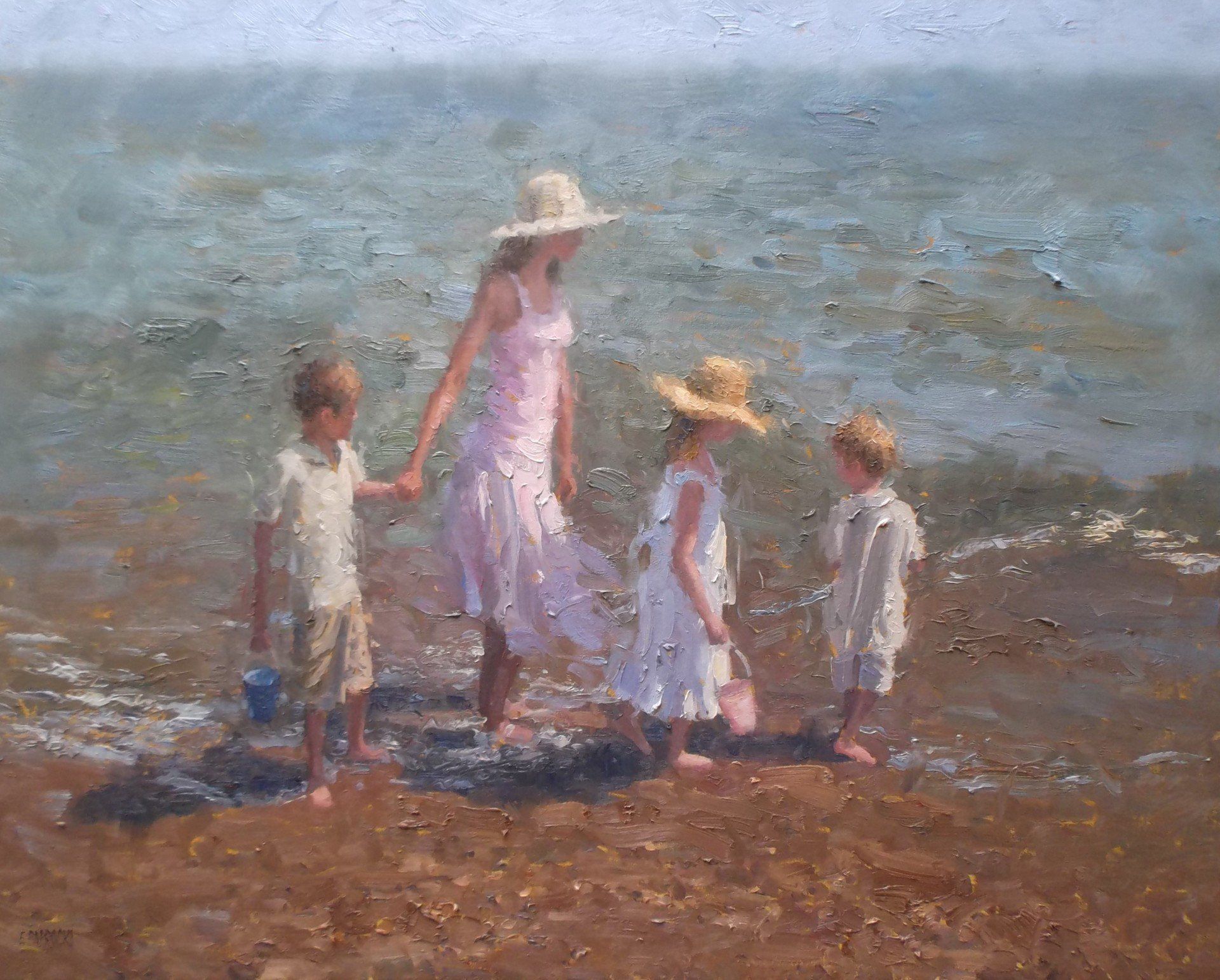 A woman and three children are walking on the beach holding hands.