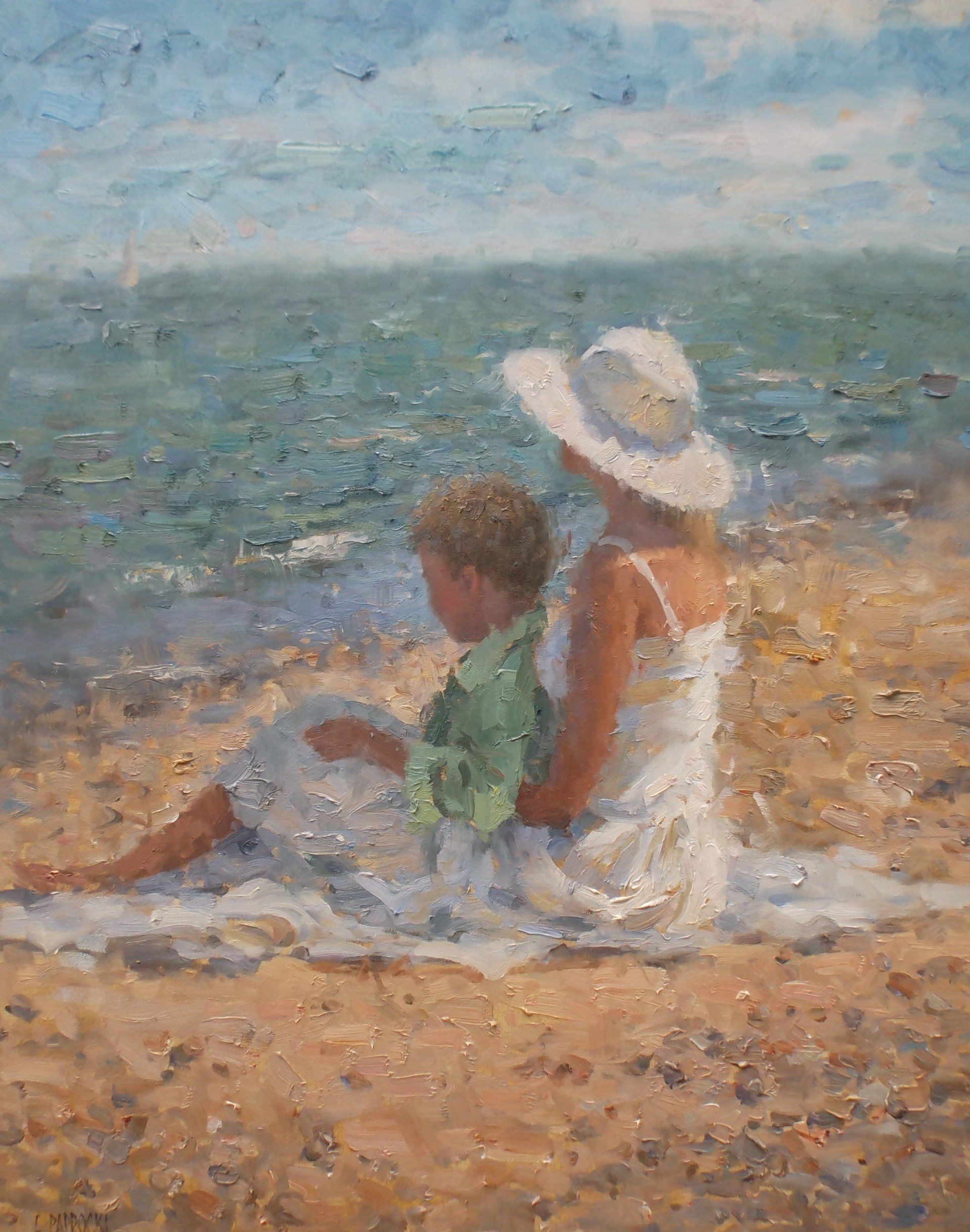 A woman and a child are sitting on the beach looking at the ocean.