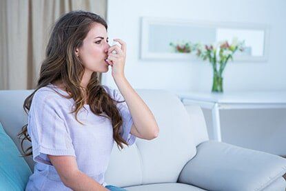 Woman Taking her Inhaler — Allergy Clinic in Idaho Falls, ID