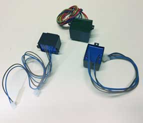 Tre piccole scatole elettroniche con fili colorati su una superficie bianca.