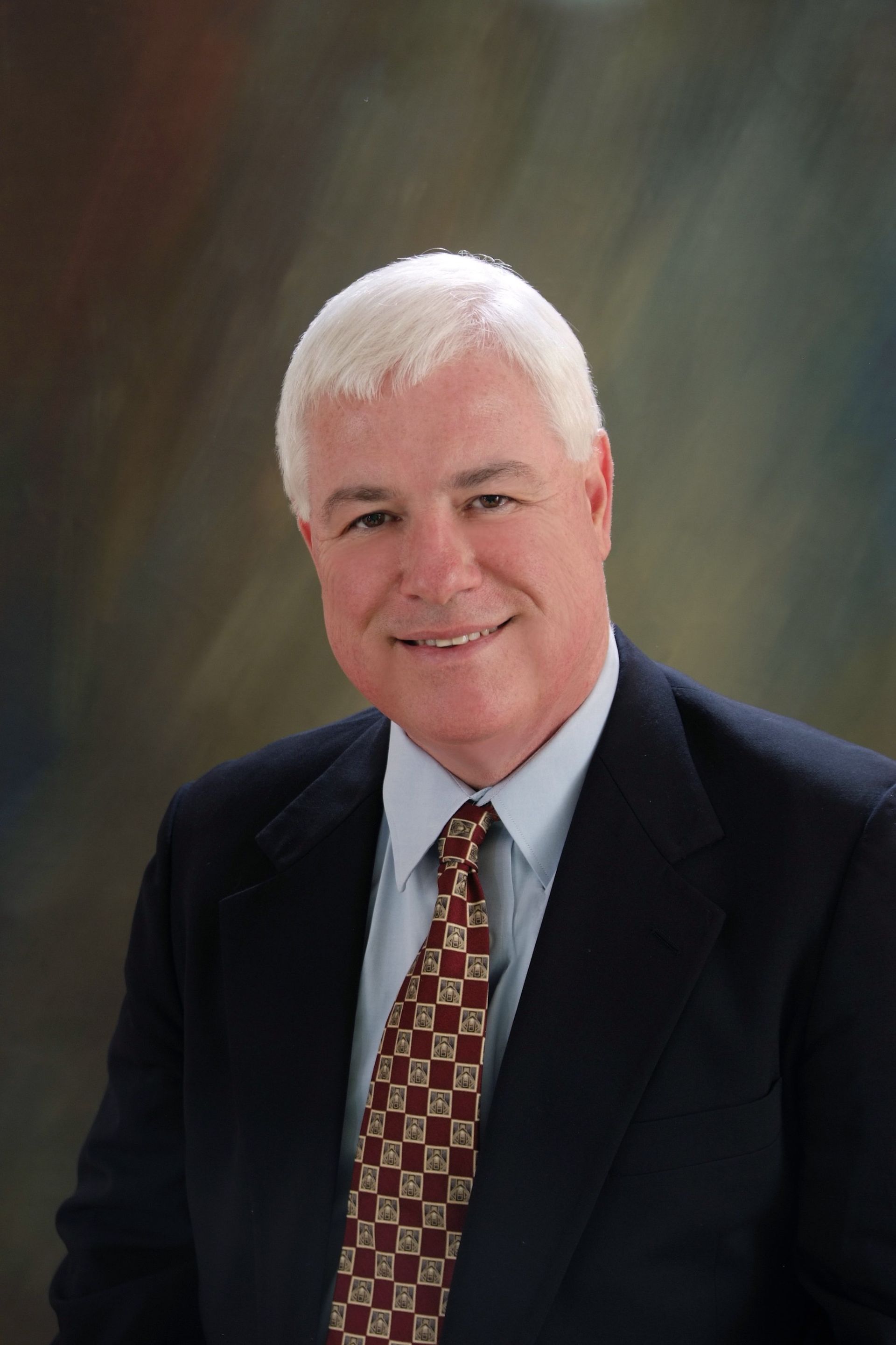 A man in a suit and tie is smiling for the camera