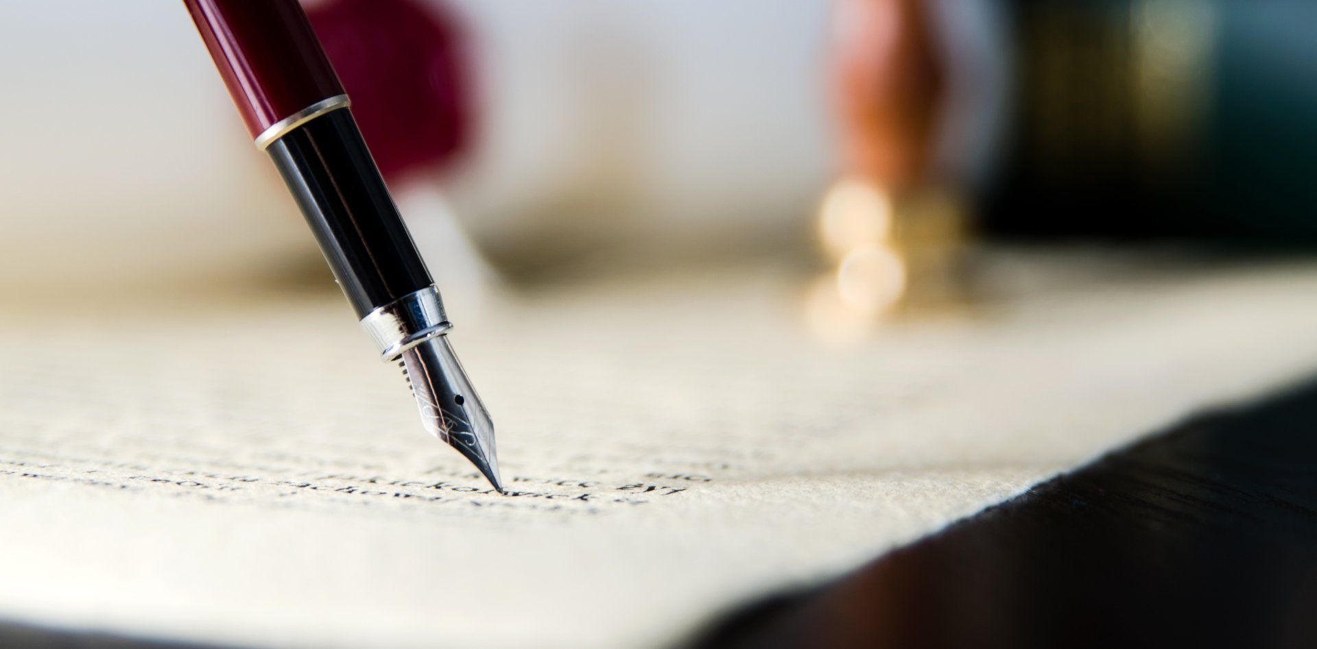 A person is writing with a fountain pen on a piece of paper.