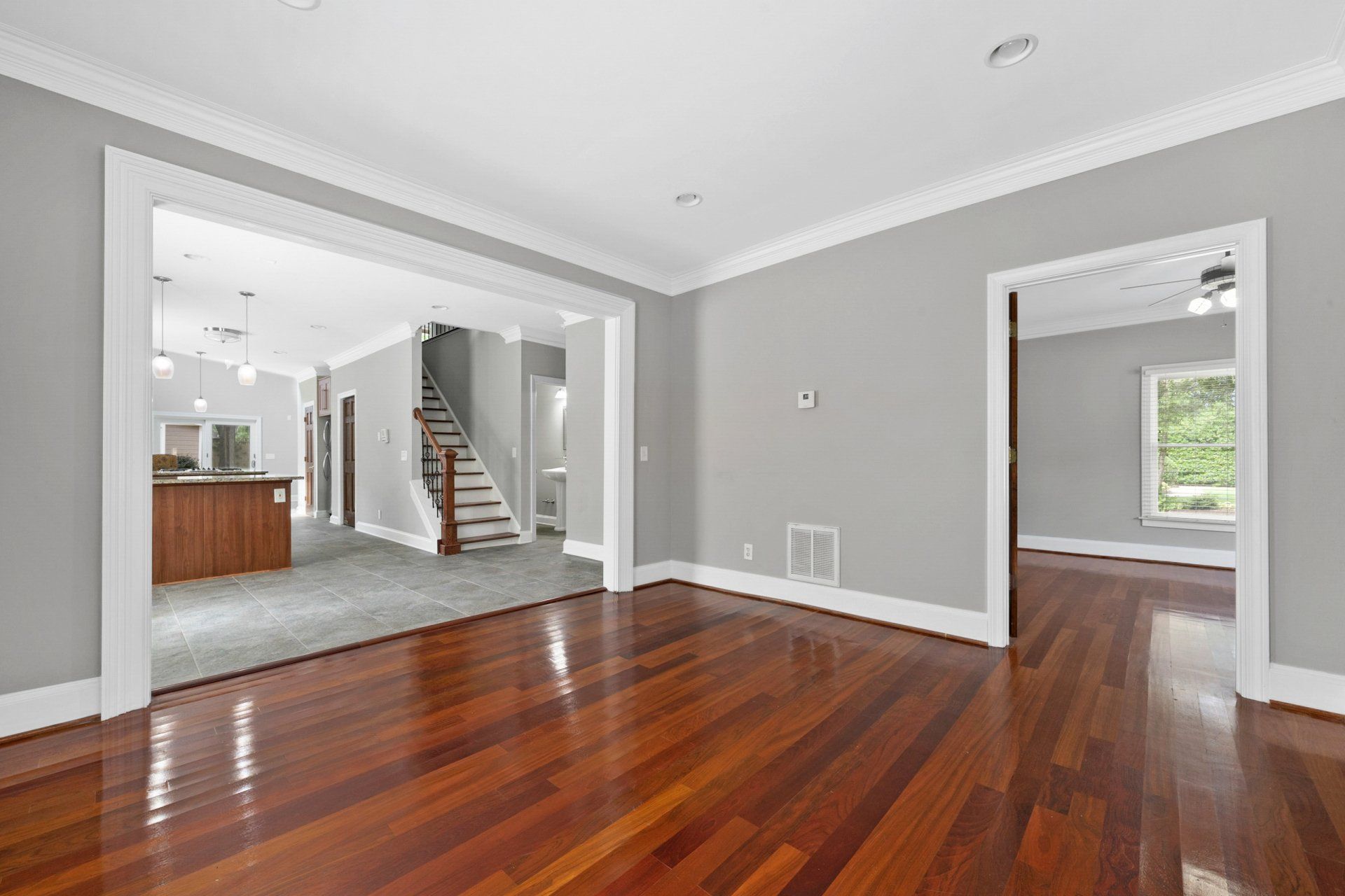 An empty living room with hardwood floors and gray walls.
