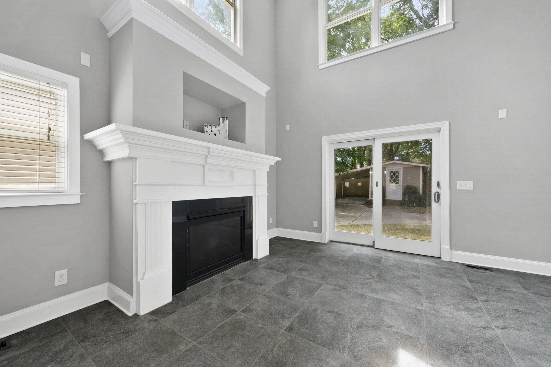 An empty living room with a fireplace and sliding glass doors.