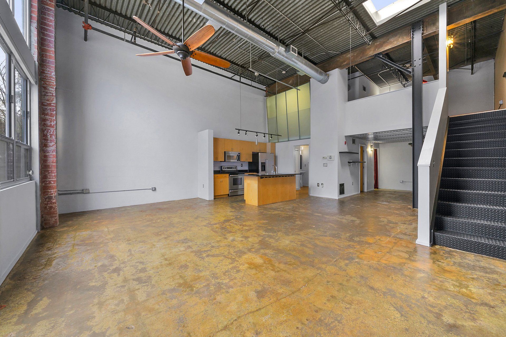 A large empty room with a kitchen and stairs