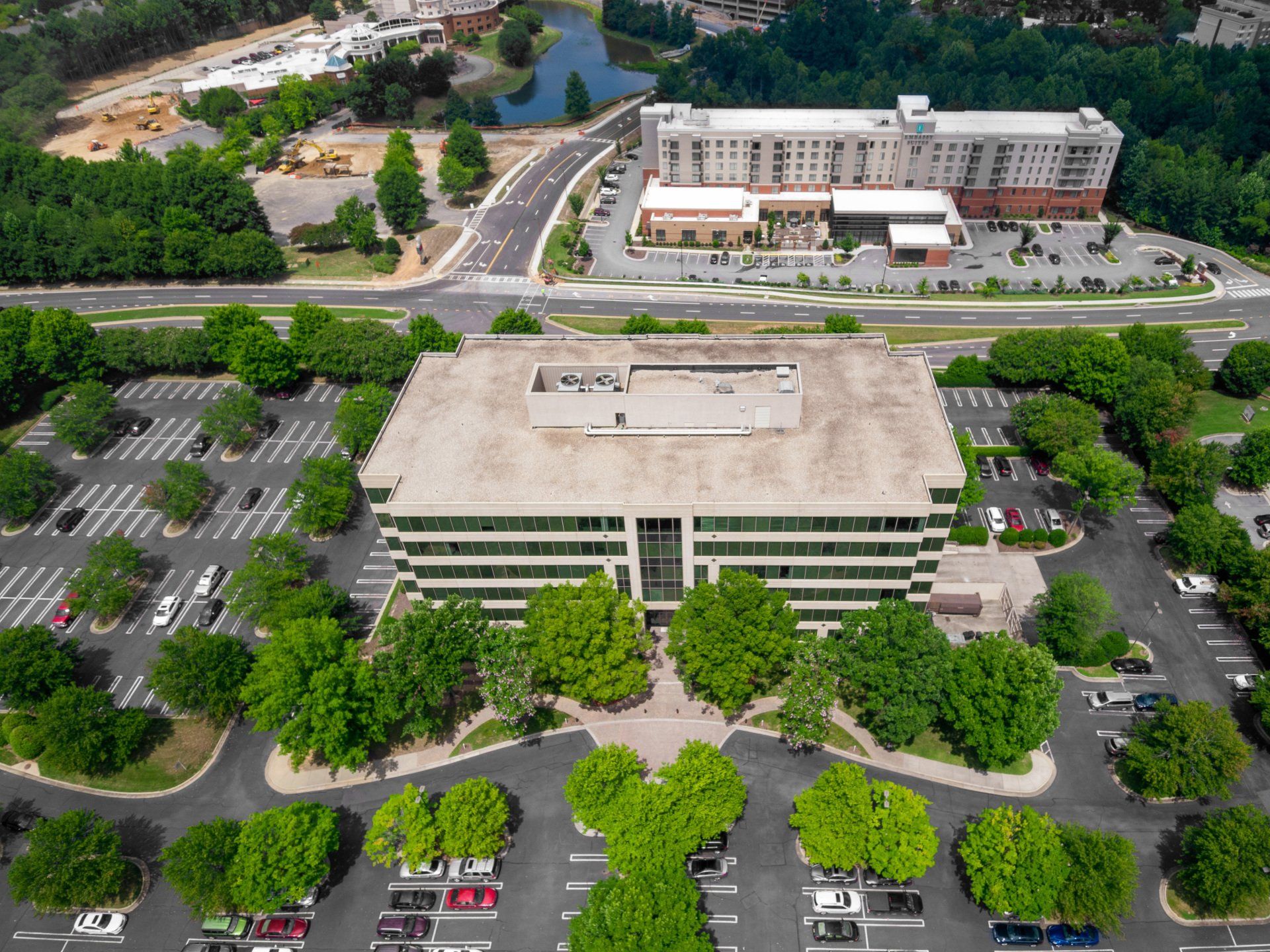 An aerial view of a large building surrounded by trees and parking lots