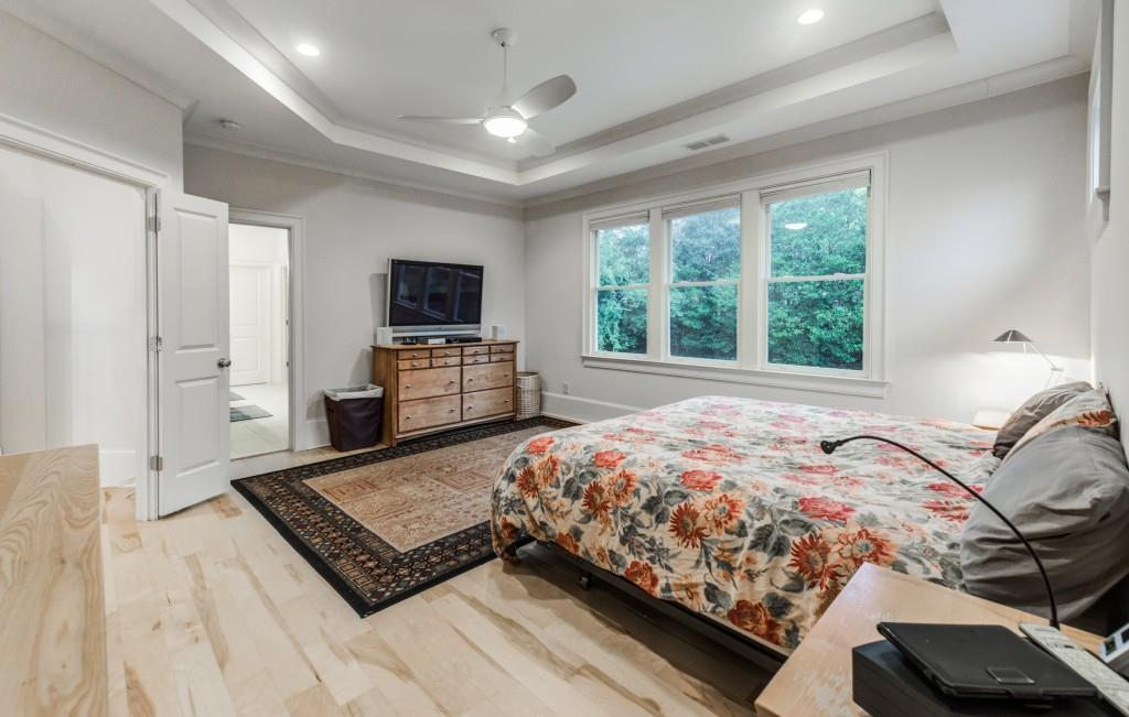 A bedroom with a large bed , a television , a rug and a ceiling fan.