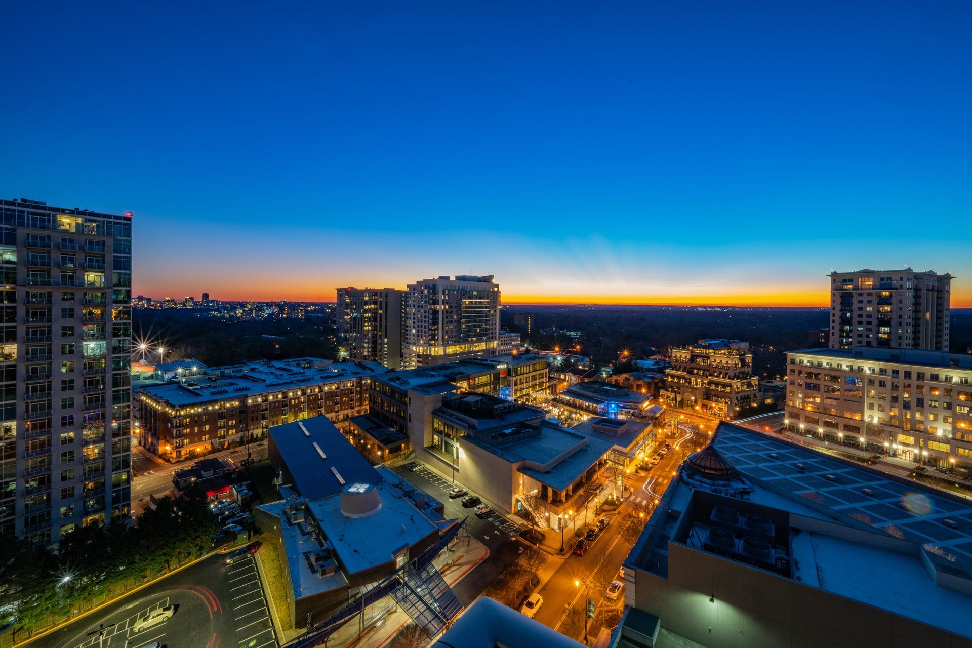 An aerial view of a city at night with a sunset in the background.