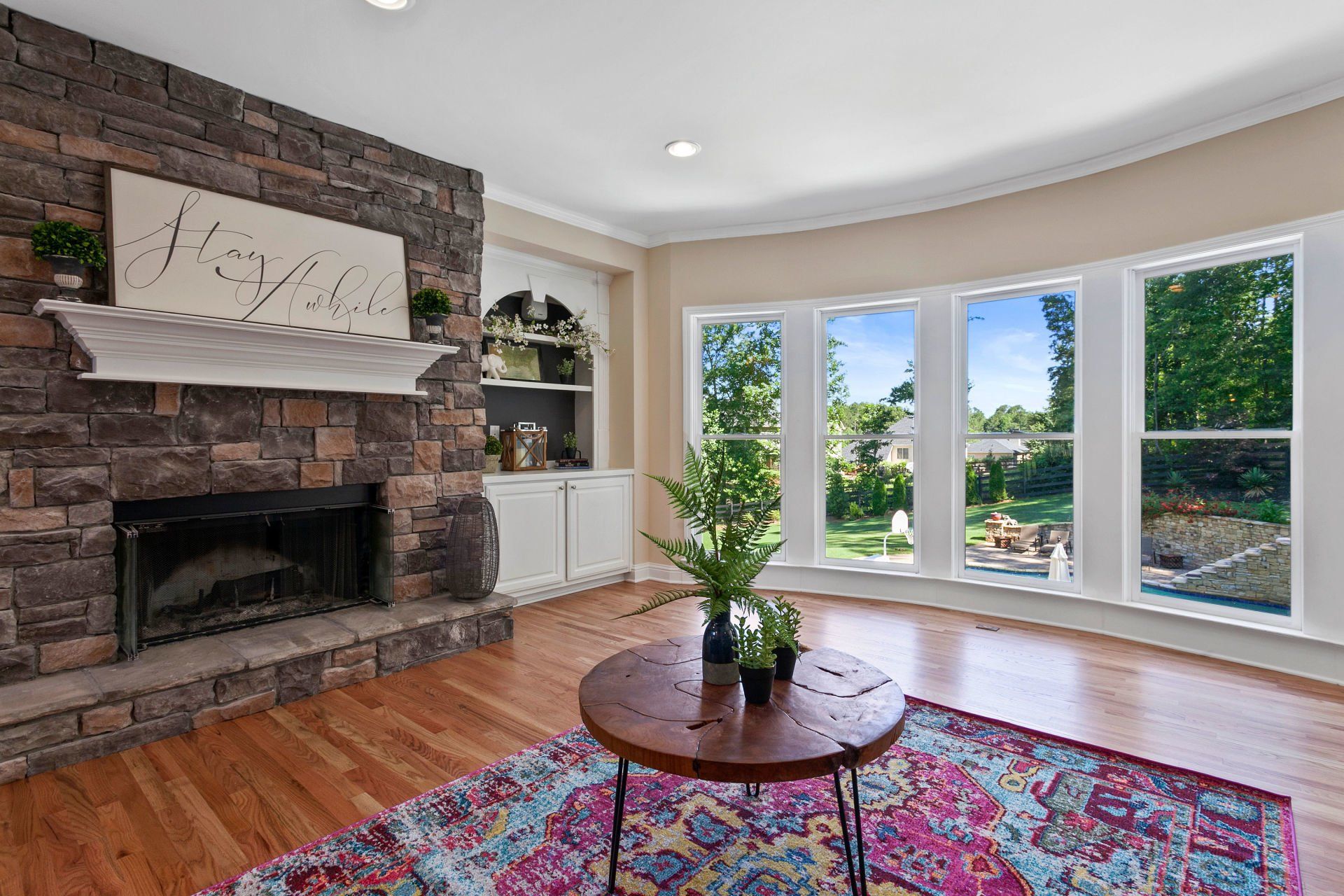 A living room with a fireplace , rug , table and windows.