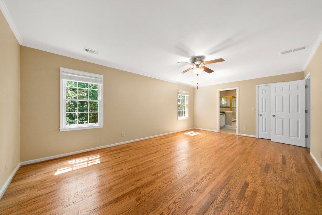 An empty living room with hardwood floors and a ceiling fan.