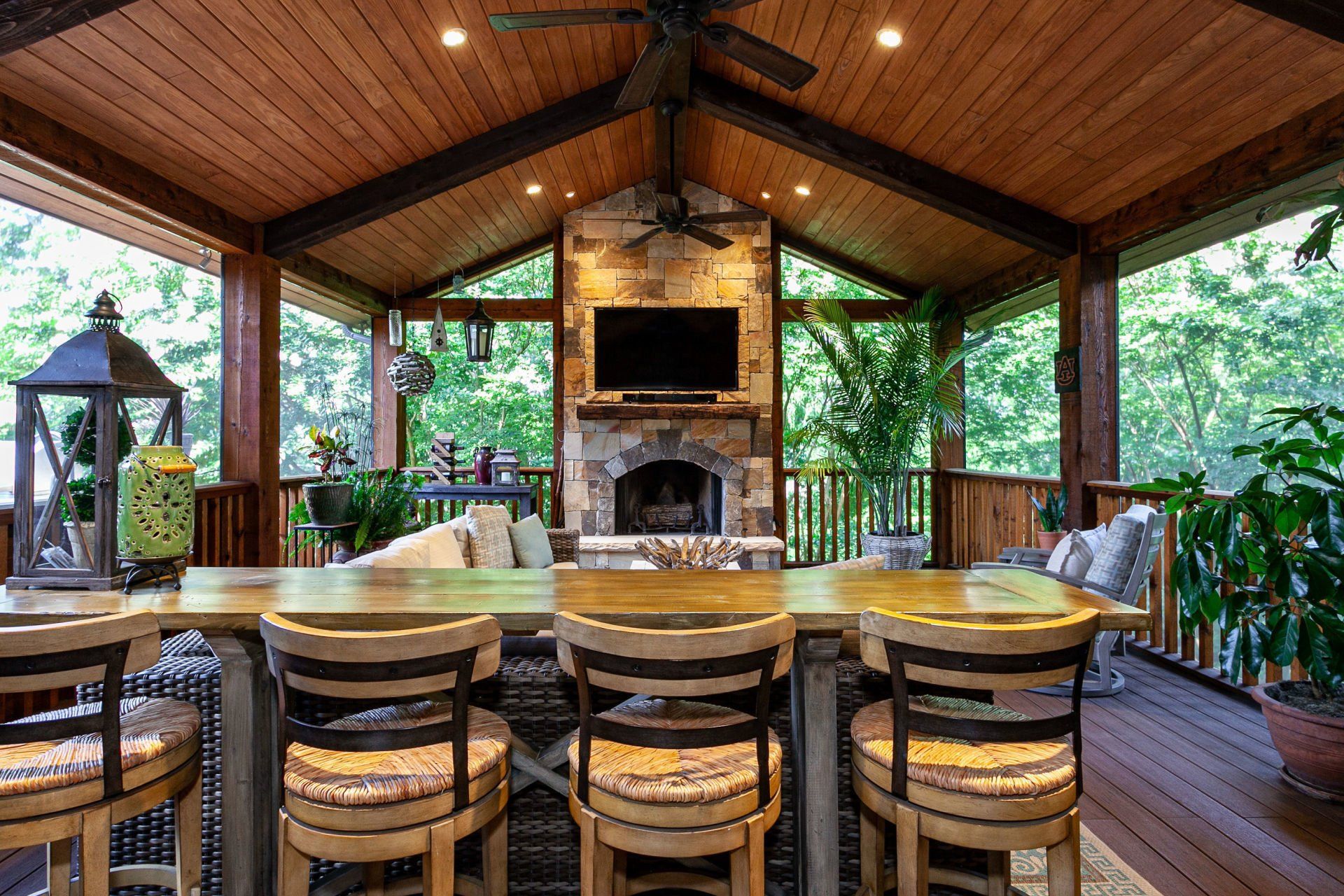 A large covered porch with a table and chairs and a fireplace.