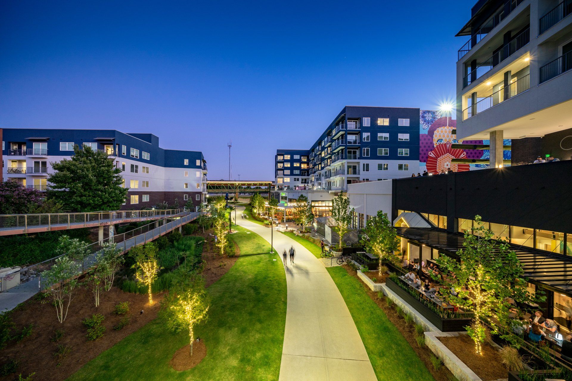 A group of people are walking down a path in a city at night.