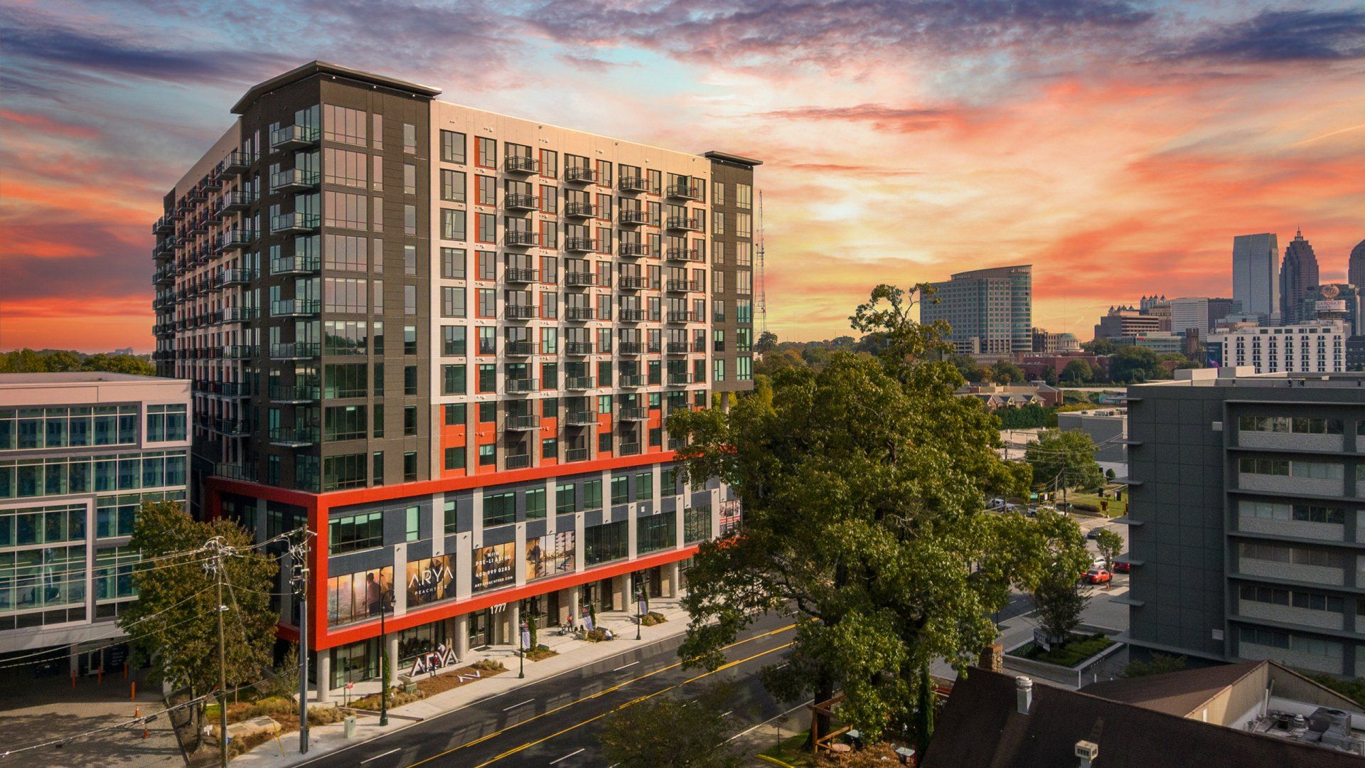 An aerial view of a large apartment building in a city at sunset.