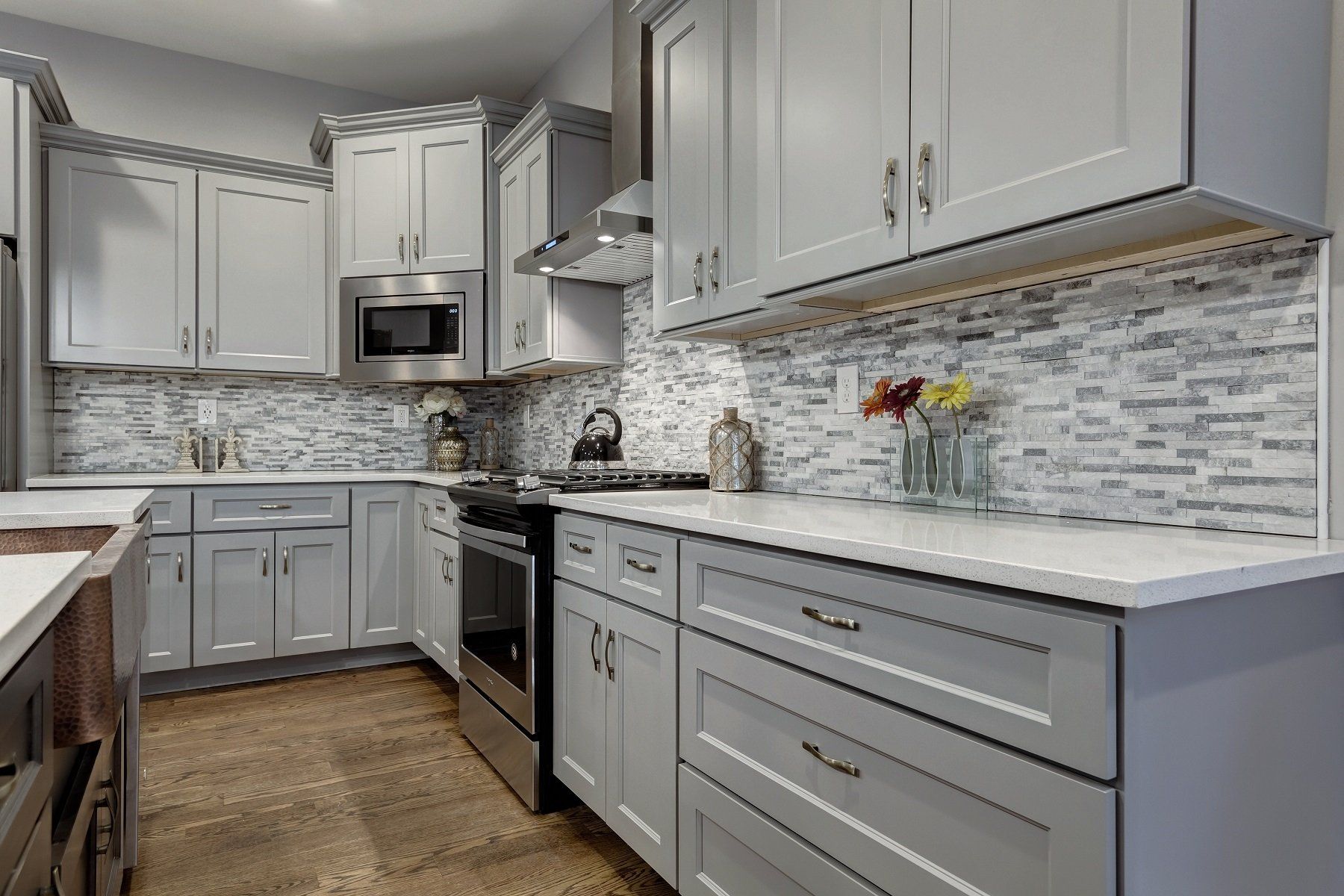 Modern kitchen with white cabinets, gray mosaic backsplash, stainless steel appliances, and gray drawers