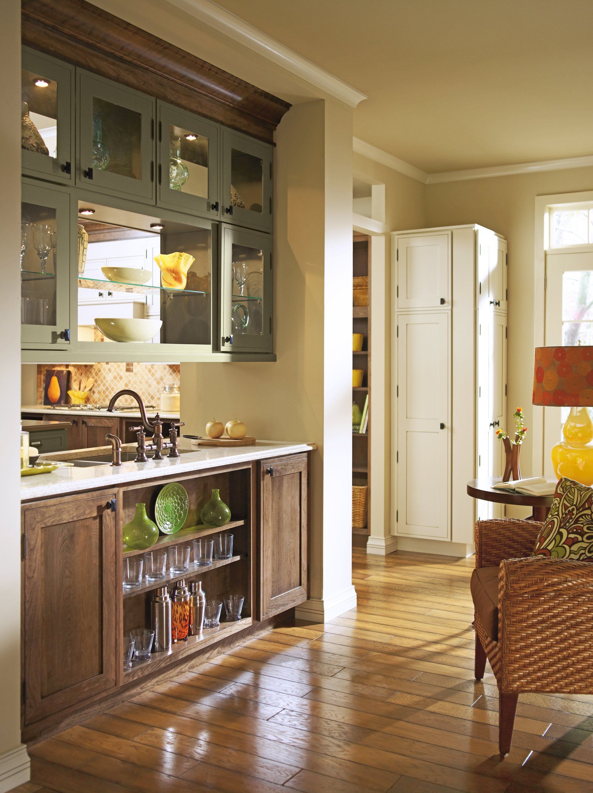 Bright kitchen with wood cabinets, countertop, and a wicker chair near sunlit windows