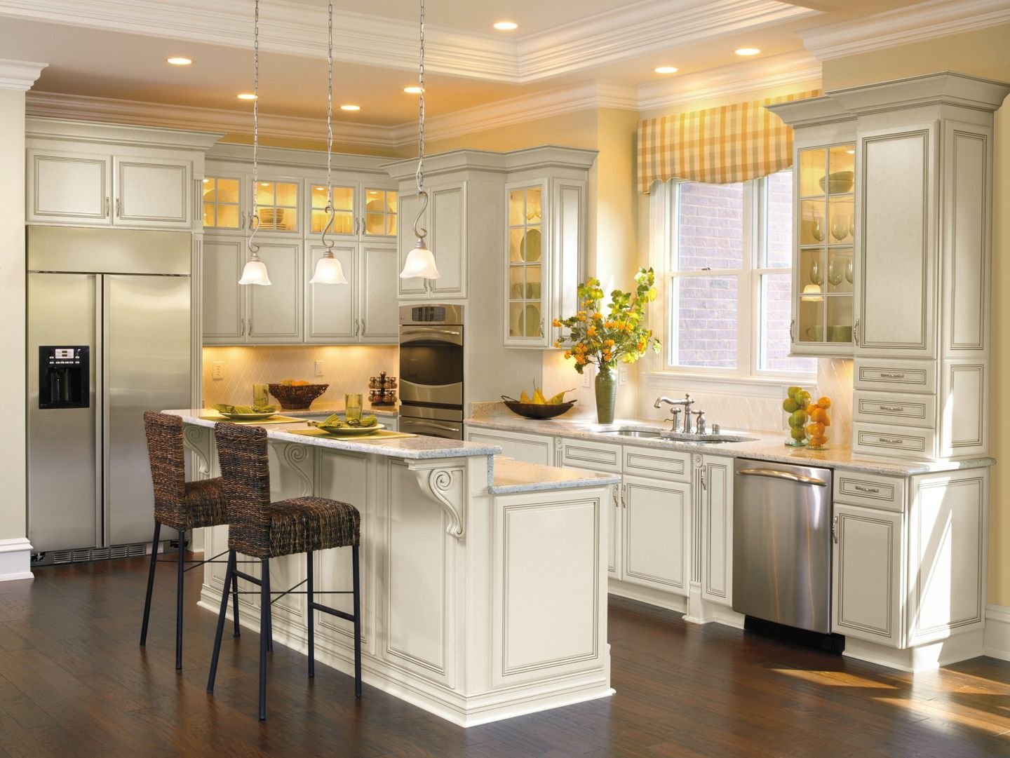 Elegant white kitchen with island, pendant lights, barstools, stainless appliances, and dark wood floors